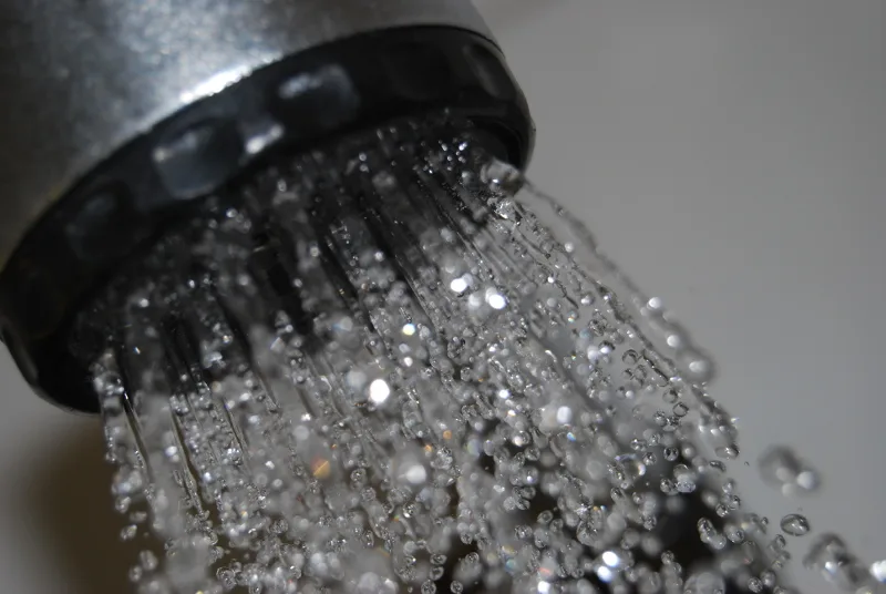 Chromen douchekop met stromend water, close-up.